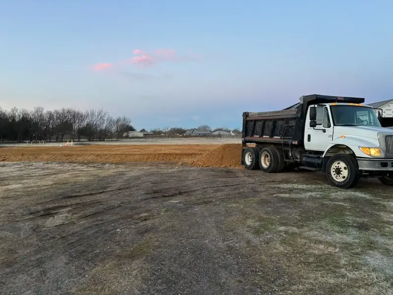 Dump truck spreading fill material for a new house pad