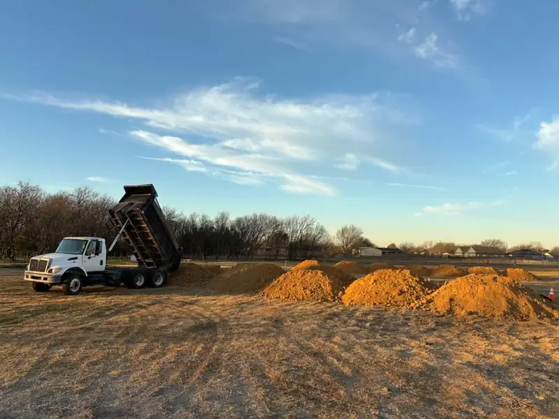 Dump truck delivering select fill dirt at golden hour