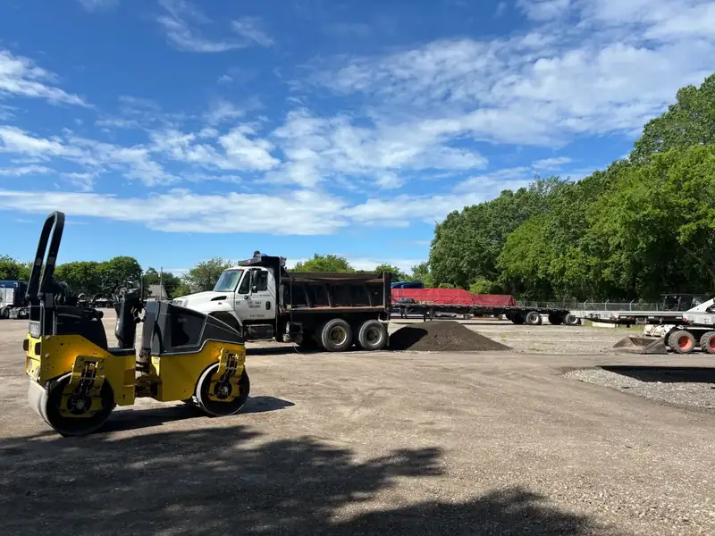 Roller compactor and dump truck finishing a commercial parking lot