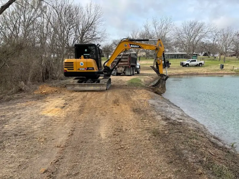 Repaired pond dam with SANY excavator and dump truck on a packed access lane