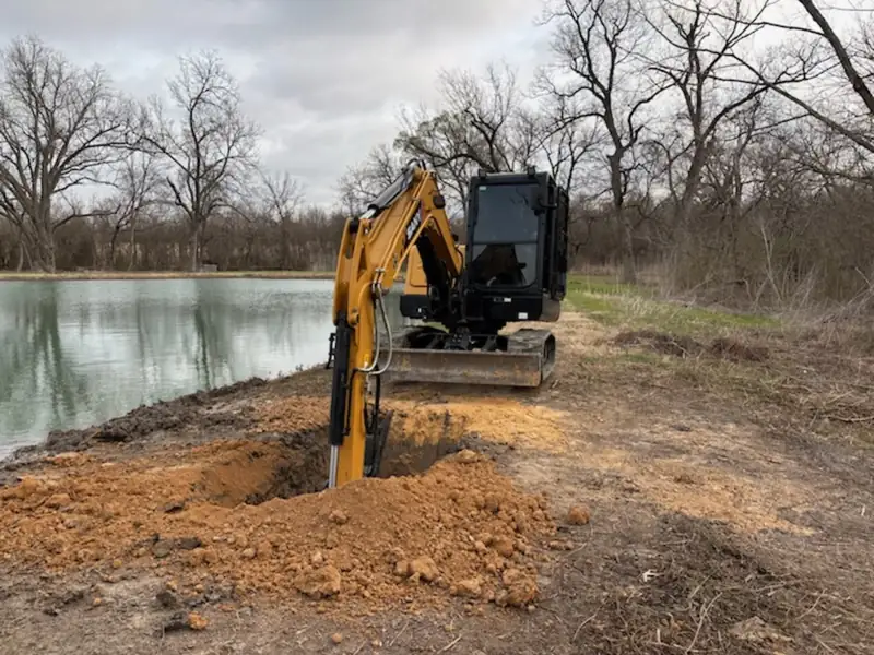 SANY excavator digging fresh dirt along the pond bank for a dam repair